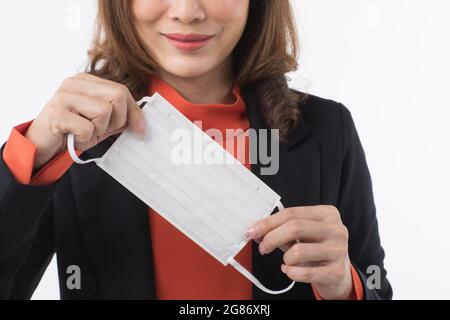 Schöne asiatische Frau in Anzug Business-Kleid auf weißem Hintergrund zeigen und demonstrieren, wie man chirurgische Hygiene schützen Maske auf Gesicht zu schützen o tragen Stockfoto