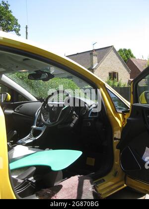 Modifiziertes Fahrzeug für behinderte Fahrer mit Lenkhilfe, Drosselklappe und Bremsanpassung, Pedalausblendung und blauem Verteilerbrett auf dem Sitz Stockfoto