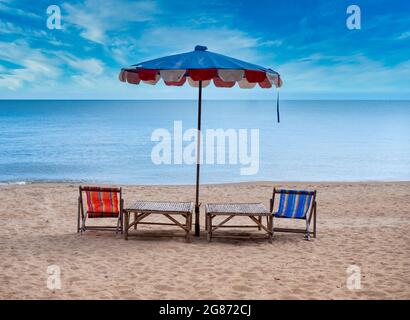 Zwei Stühle mit Sonnenschirm am Strand in schönem Himmel. Sommerurlaub und Urlaubskonzept. Stockfoto