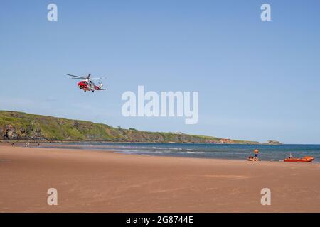 Lunan Bay Beach, Angus, Schottland, Großbritannien, 17. Juli 2021: Große Rettungsaktion der Küstenwache und RNLI, nachdem eine Mutter und Tochter heute am Lunan Bay Beach mit ihrem aufblasbaren Schlauchboot bei starkem Wind auf See getrieben wurden. Ein Offshore-Versorgungsschiff, das sich in der Nähe befand, startete ebenfalls seinen FRC, um bei der Rettung zu helfen. Auf diesem Foto sehen Sie den Küstenwachhubschrauber, der am Strand an Land kommt. (Quelle: Barry Nixon/Alamy Live News) Stockfoto