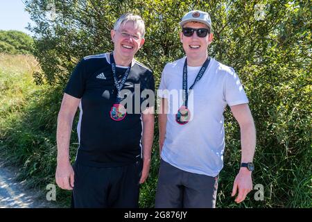 Rossarbery, West Cork, Irland. Juli 2021. Die Temperaturen erreichten heute in Rosscarbery 27 Grad, während der Warren Beach voller Sonnenanbeter war. Die Galey Head Schwimm fand heute statt, wo die Teilnehmer schwammen von Red Strand zum Warren Beach, eine Entfernung von 10 KM. Nach dem Schwimmen mit ihren Medaillen sind Jim Dunne, Co. Meath und Jason Prior, Leixlip, zu sehen. Quelle: AG News/Alamy Live News Stockfoto