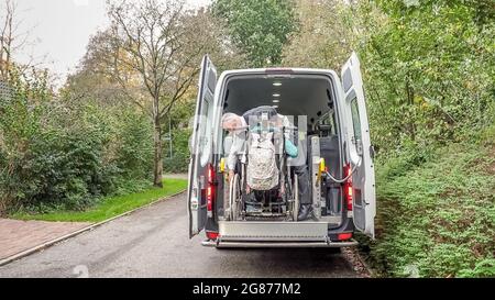 Einer behinderten Person im Rollstuhl wurde geholfen, in einen speziell angepassten Schulbus zu gelangen. Stockfoto