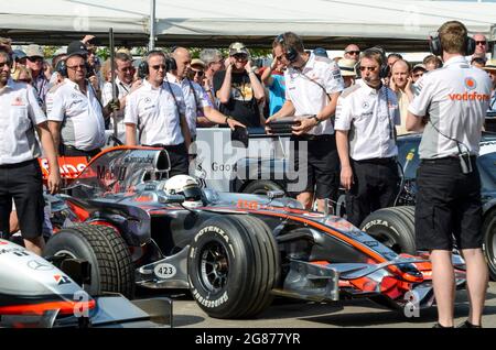 McLaren MP4-23 Formel-1-Grand-Prix-Rennwagen beim Goodwood Festival of Speed 2013, umgeben von Ingenieuren, die startbereit sind Stockfoto