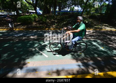 La Libertad, El Salvador. Juli 2021. Ein Mann und seine Tochter fahren mit dem Fahrrad in einem Park. El Salvador verzeichnet 82,852 bestätigte Fälle und 2,484 Todesfälle, da das Land täglich einen Anstieg verzeichnet. (Bild: © Camilo Freedman/ZUMA Press Wire) Stockfoto