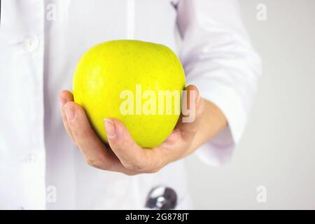 Doktor hält grünen Apfel. Großer grüner Apfel in der Hand des Arztes. Gesundheit in Ihren Händen. Stockfoto