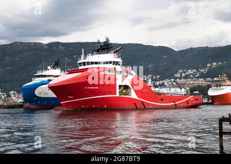 Offshore AHTS Anker Handling Schlepper Versorgungsschiff KL Sandefjord Abfahrt aus dem Hafen von Bergen, Norwegen. Vorbei am Offshore-Schiff Hermit Galaxy in Skoltegr Stockfoto