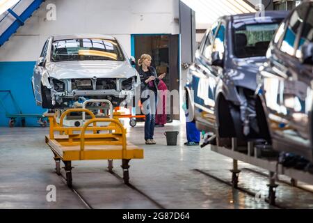 Kostanay, Kasachstan, 14.Mai2012: Saryarkaavtoprom Auto-Building-Anlage. Ssangyong Automobilproduktion. Junge Arbeiterin Frau auf Karosserie Lackierung Qualität Stockfoto