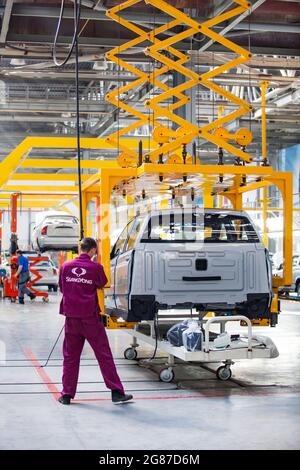 Kostanay, Kasachstan, 14.Mai2012: Saryarkaavtoprom Auto-Building-Anlage. Ssangyong Autos Montage. Arbeiter verwenden Gelbe Manipulator Pantograph Hoist t Stockfoto