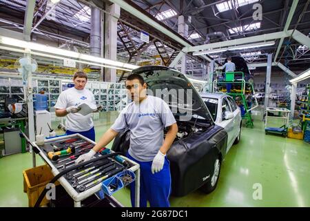 USt'-Kamenogorsk, Kasachstan, Mai 31,2012: Auto-Gebäude der Firma Asia-Auto. Arbeiter und Auto auf Montageband.Werkzeugwagen (links). Stockfoto