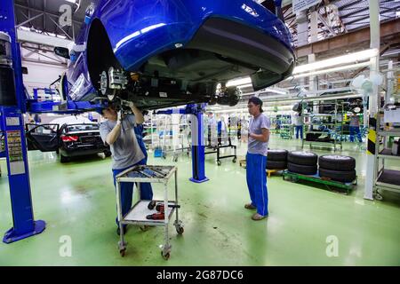 USt'-Kamenogorsk,Kasachstan,31.Mai2012:Asia-Auto Firmenwerk.zwei Arbeiter in blauen Kappen und Hosen, graue T-Shirts, die Autoaufhängung montieren. Stockfoto