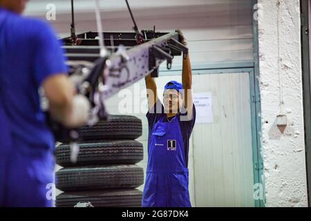 Almaty Region, Kasachstan-Juni 06,2012:Astana-Motors Unternehmen Auto-Gebäude Werk.Hyundai Busse Montage.Junge lächelnde Arbeiter in blauer Kleidung hält Teil. Stockfoto