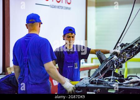 Region Almaty, Kasachstan, 06. Juni 2012: Autofabrik der Firma Astana-Motors. Hyundai-Busse montieren. Zwei junge Arbeiter und Stahlbus-Chassis. Stockfoto