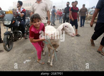 Rafah, Gaza. Juli 2021. Ein palästinensisches Mädchen spielt mit Schafen auf einem Viehmarkt vor Eid al-Adha in Rafah, im südlichen Gazastreifen, am Samstag, den 17. Juli, 2021. Muslime auf der ganzen Welt feiern Eid al-Adha, indem sie die Gräber ihrer Angehörigen besuchen und Schafe, Ziegen, Kühe und Kamele schlachten, zum Gedenken an die Bereitschaft des Propheten Abraham, seinen Sohn Ismail auf Gottes Befehl zu opfern. Foto von Ismael Mohamad/UPI Credit: UPI/Alamy Live News Stockfoto