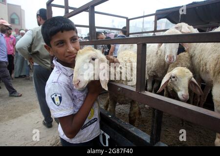 Rafah, Gaza. Juli 2021. Ein palästinensischer Junge spielt am Samstag, den 17. Juli 2021, auf einem Viehmarkt vor dem Eid al-Adha in Rafah im südlichen Gazastreifen mit Opfertieren. Muslime auf der ganzen Welt feiern Eid al-Adha, indem sie die Gräber ihrer Angehörigen besuchen und Schafe, Ziegen, Kühe und Kamele schlachten, zum Gedenken an die Bereitschaft des Propheten Abraham, seinen Sohn Ismail auf Gottes Befehl zu opfern. Foto von Ismael Mohamad/UPI Credit: UPI/Alamy Live News Stockfoto