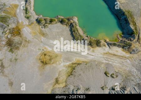 Luftaufnahme aus einer Tongrube mit einem riesigen grünen See zur Sandgewinnung in der Granitkarriere Stockfoto