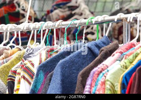 Nahaufnahme von Kleidung, die auf einem Regal im Resale Shop auf der Straßenmesse im Freien hängt. Gebrauchte Kleidung. Stockfoto