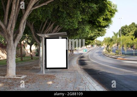 Weiße leere vertikale Plakatwand an der Bushaltestelle auf der Stadtstraße. Schild auf der Straße am Straßenrand. Stockfoto