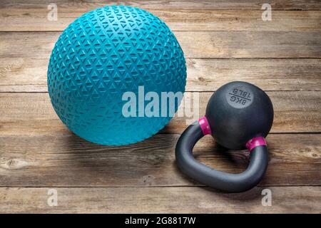 Schwerer, mit Sand und kleiner eiserner Kugelhantel gefüllter Gummiball auf rustikalem Holzhintergrund, Trainings-, Bewegungs- und Fitnesskonzept Stockfoto