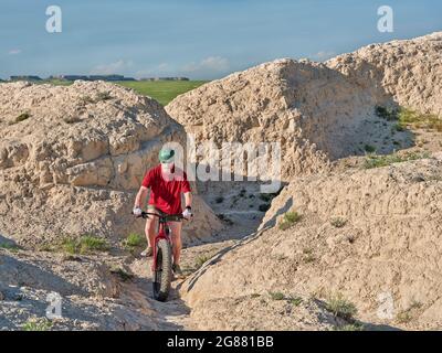 Ein älterer Radler fährt auf einem fetten Mountainbike entlang arroyo in den Badlands des Pawnee National Grassland im Norden Colorados Stockfoto