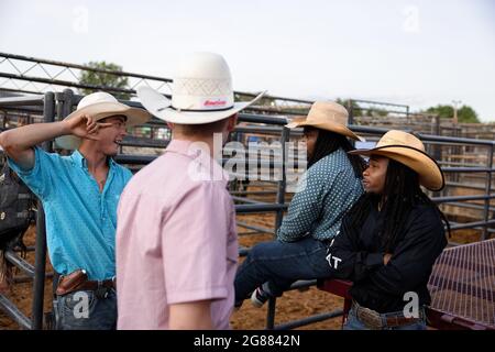 Bloomington, Usa. Juli 2021. Rodeo-Cowboys unterhalten sich während des 3 Bar J Rodeo auf der Monroe County Fair zwischen den Veranstaltungen. Die Monroe County Fair in Bloomington, Indiana, ist eine einwöchige Ausstellung für Kunsthandwerk, landwirtschaftliche Produkte und Viehzucht, ein Gemeindetreffen und ein Festival, das auf dem County Fairgrounds stattfindet. County Messen in den USA sind eine Tradition und Teil der Kultur tief in ländlichen amerikanischen Leben verwurzelt. County Messen begann vor langer Zeit als eine Möglichkeit für Landwirte und landwirtschaftliche Arbeitnehmer zu sammeln und Kontakte zu knüpfen. (Foto von Jeremy Hogan/SOPA Images/Sipa USA) Quelle: SIPA USA/Alamy Live News Stockfoto