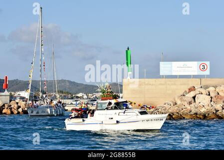 Ein Blick auf ein Boot, das mit einer Statue der Virgen del Carmen während der Seefahrt Prozession in Vendrell führt. Jedes Jahr am 16. Juli wird ein religiöses Fest zu Ehren der Virgen del Carmen, der schutzpatronin der Seefahrer und Fischer, gefeiert, obwohl die Feier am 16. Juli stattfindet, die Prozession am Wochenende stattfindet, damit mehr Menschen an der Feier teilnehmen können. Die Statue der Jungfrau, wird von einer Gruppe von Menschen, die es zu einem Boot verlassen während der Prozession durch das Wasser des Meeres in der Nähe des Hafens, gefolgt von mehreren Booten getragen. Stockfoto