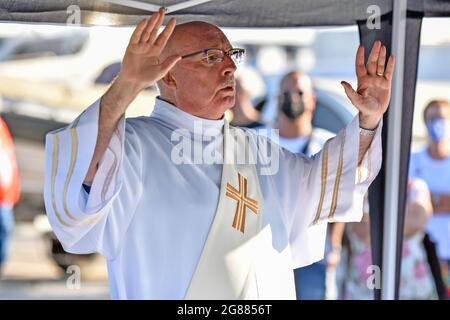 Jose Antonio Fernandez der Priester Diakon der Gemeinde Vendrell gesehen am Hafen von Coma-ruga während der maritimen Prozession der Virgen del Carmen in Vendrell. Jedes Jahr am 16. Juli wird ein religiöses Fest zu Ehren der Virgen del Carmen, der schutzpatronin der Seefahrer und Fischer, gefeiert, obwohl die Feier am 16. Juli stattfindet, die Prozession am Wochenende stattfindet, damit mehr Menschen an der Feier teilnehmen können. Die Statue der Jungfrau, wird von einer Gruppe von Menschen, die es zu einem Boot verlassen während der Prozession durch das Wasser des Meeres in der Nähe des Hafens, gefolgt von mehreren Booten getragen. Stockfoto