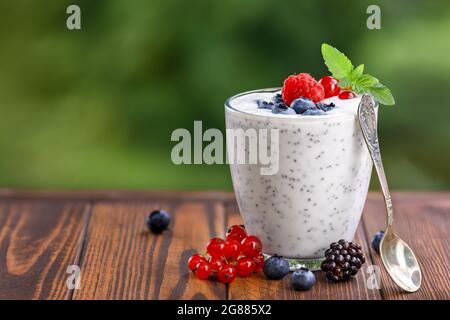 chia Pudding mit Joghurt und frischen Beeren im Glas auf dem Tisch im Freien Stockfoto