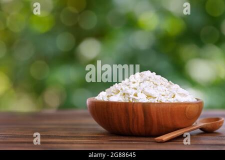 Hüttenkäse in Holzschüssel auf dem Tisch im Freien Stockfoto