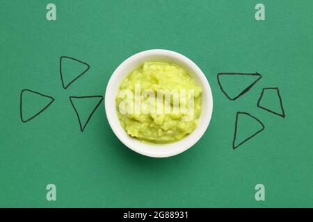 Kreative Komposition mit leckerer Guacamole auf farbigem Hintergrund Stockfoto