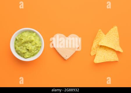 Kreative Komposition mit leckeren Guacamole und Nachos auf farbigem Hintergrund Stockfoto