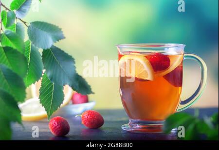 Frisch gebrühter Tee mit Zitrone und Erdbeeren in einer großen Glasschale Stockfoto