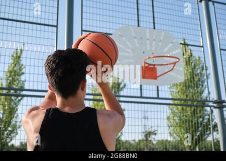 Rückansicht eines Basketballspielers, der den Ball in den Korb wirft. Basketball schießen. Stockfoto