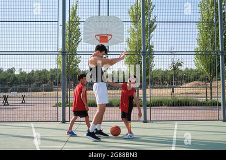 Geschwister lachen und fivieren mit ihrem älteren Bruder, einer von ihnen hat eine Beinprothese. Älterer Bruder motiviert Kinder während der Auszeit. Stockfoto