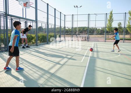 Drei Brüder spielen Fußball, einer von ihnen hat eine Beinprothese und tritt eine Strafe. Geschwister spielen zusammen Sport. Stockfoto