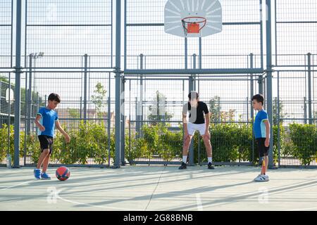 Drei Brüder spielen Fußball, einer von ihnen hat eine Beinprothese und der andere tritt eine Strafe. Geschwister spielen zusammen Sport. Stockfoto