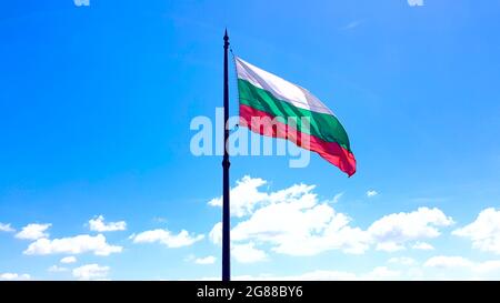 Bulgarische Nationalflagge schwenkt auf Fahnenmast gegen den blauen Himmel. Bulgarien Stockfoto