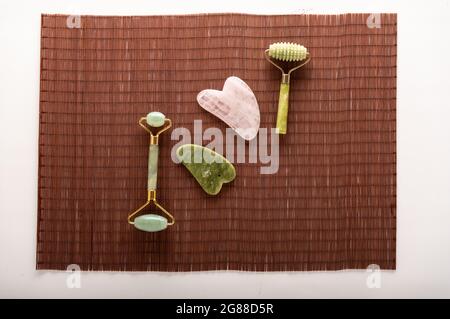 Rollen und Steine für Leder. Natursteine zur Glättung der Haut. Kosmetische Werkzeuge auf einer Bambusmatte. Draufsicht. Stockfoto