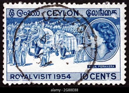 SRI LANKA - UM 1954: Eine in Sri Lanka gedruckte Briefmarke zeigt die königliche Prozession, den Besuch von Königin Elizabeth II. Und dem Herzog von Edinburgh, um 1954 Stockfoto