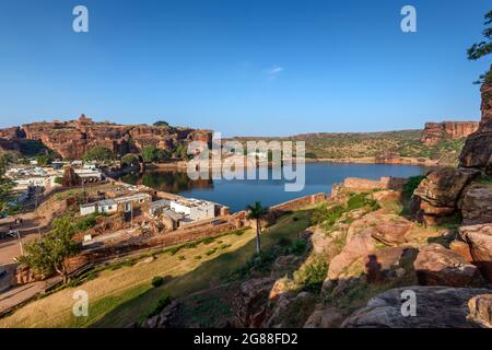 Badami, Karnataka, Indien - 10. Januar 2020 : Agasthya See und die umliegenden roten Felshügel. Einige braune Steintempelgebäude streuten sich herum, Badami Stockfoto