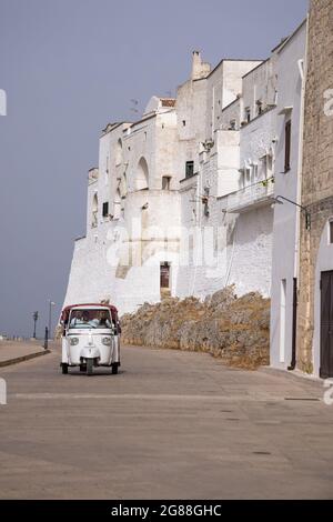 Ostuni ist eine Stadt in der italienischen Region Apulien, die für ihre weiß getünchte Altstadt bekannt ist. Stadtmauer von Ostuni mit Vespa Roller auf der Straße. Süditalien Stockfoto