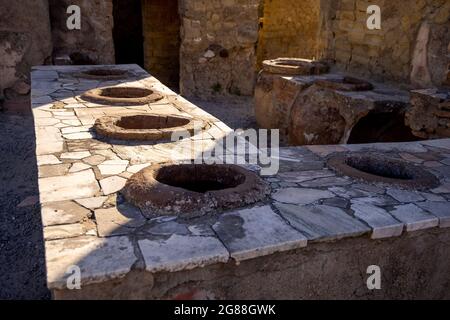 Thermopolium oder Taberna (Köchin) in Ercolano - Herculaneum, alte römische Stadt, die durch den Ausbruch des Vulkans Vesuv oder Vesuv zerstört wurde. Stockfoto