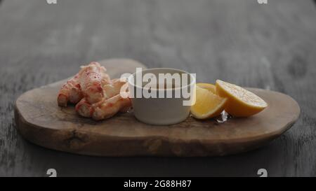 Gimbal-Shot mit Krabbenbein in Zeitlupe auf einem Olivenbrett mit süßer Zitrone und Dip-Sauce, 120 Bilder/s. Stockfoto
