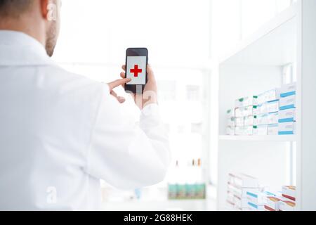 Apotheker mit einem Smartphone in seiner Apotheke. Stockfoto
