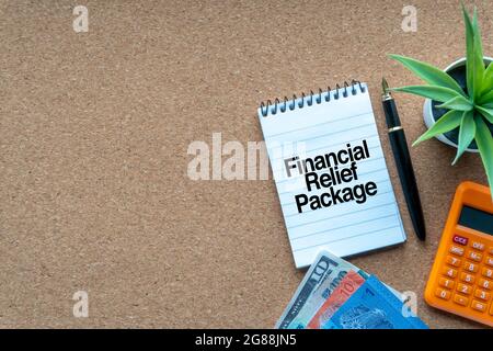FINANZHILFE-PAKETTEXT mit Notizblock, Rechner, Zierpflanze, Geldscheinen, Tastatur und Füllfederhalter auf Holzhintergrund. Unternehmen und Stockfoto