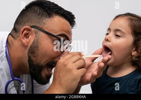 Kinderarzt untersucht die Kehle eines 3-jährigen Mädchens Stockfoto