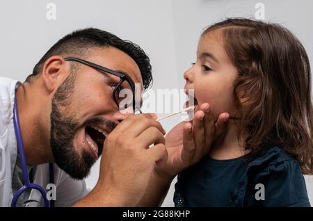 Kinderarzt untersucht die Kehle eines 3-jährigen Mädchens Stockfoto