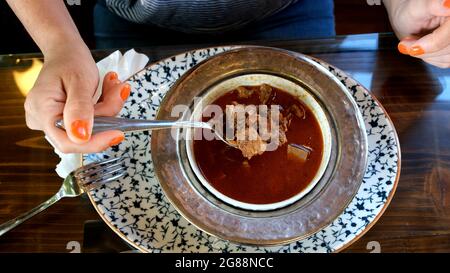 Weibliche Kundin trinkt kelle paca Suppe im Restaurant Stockfoto