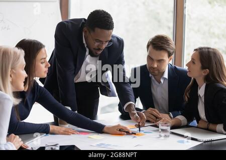 Fokussierter afroamerikanischer Wirtschaftsführer und Mitarbeiter diskutieren über das Projekt Stockfoto
