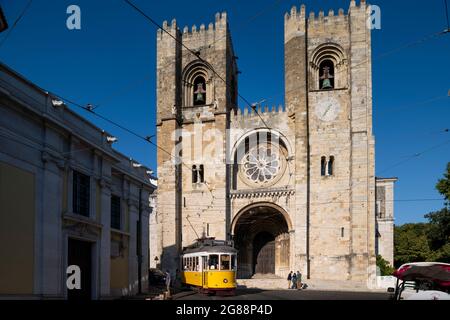 Lissabon, Portugal - 16. Juli 2021: Blick auf die Kathedrale von Lissabon (SE de Lisboa) mit einer ikonischen gelben Straßenbahn, die vor ihr vorbeifährt, in der Stadt Lissabon Stockfoto