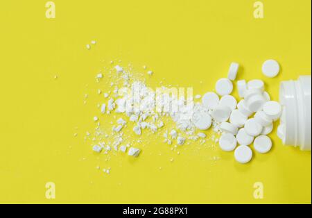 Weiße Tablette Medizin püriert und Gießen aus der Flasche auf gelbem Hintergrund Stockfoto